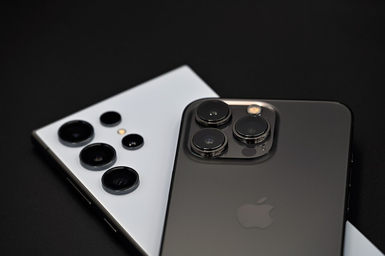 A Samsung Galaxy S24 Ultra and an iPhone 13 Pro lying back to back